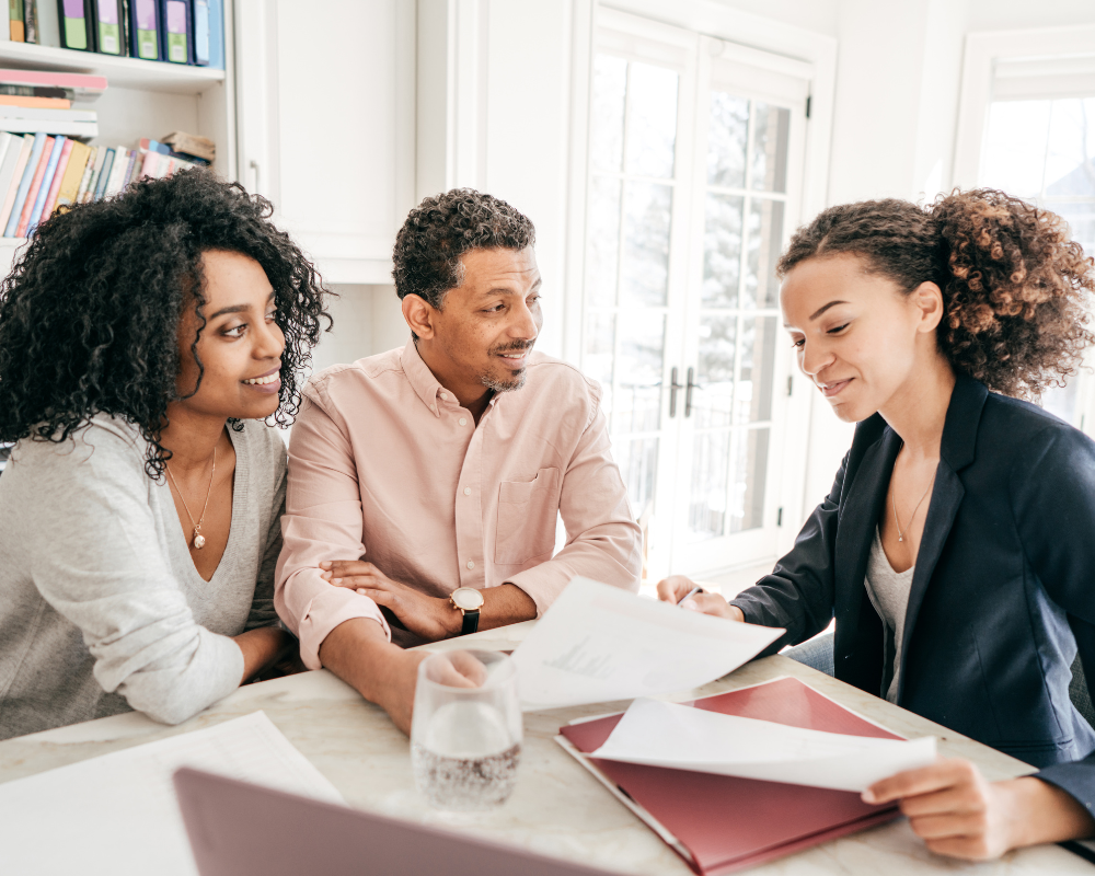 Man in a gray work uniform standing in a warehouse, smiling with arms crossed.