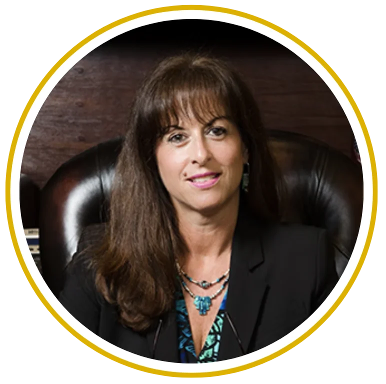 Professional woman with long dark hair wearing a black blazer, seated and smiling at the camera.
