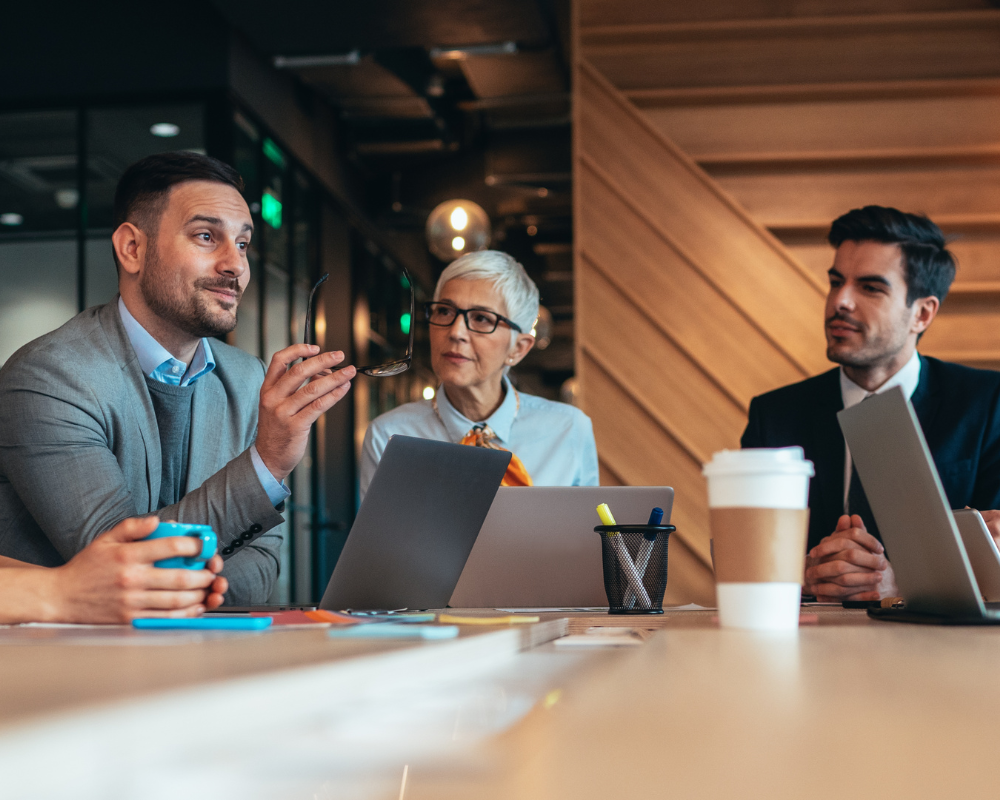 Business professionals in suits having a meeting with laptops and coffee.