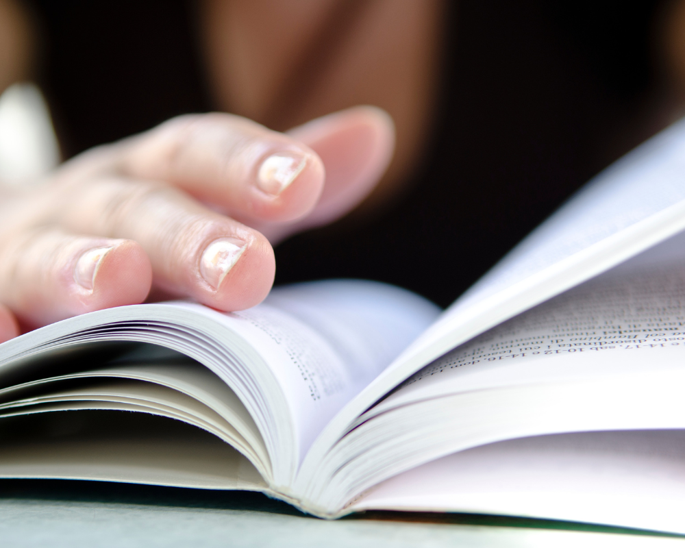 Close-up of a hand flipping through the pages of an open book.