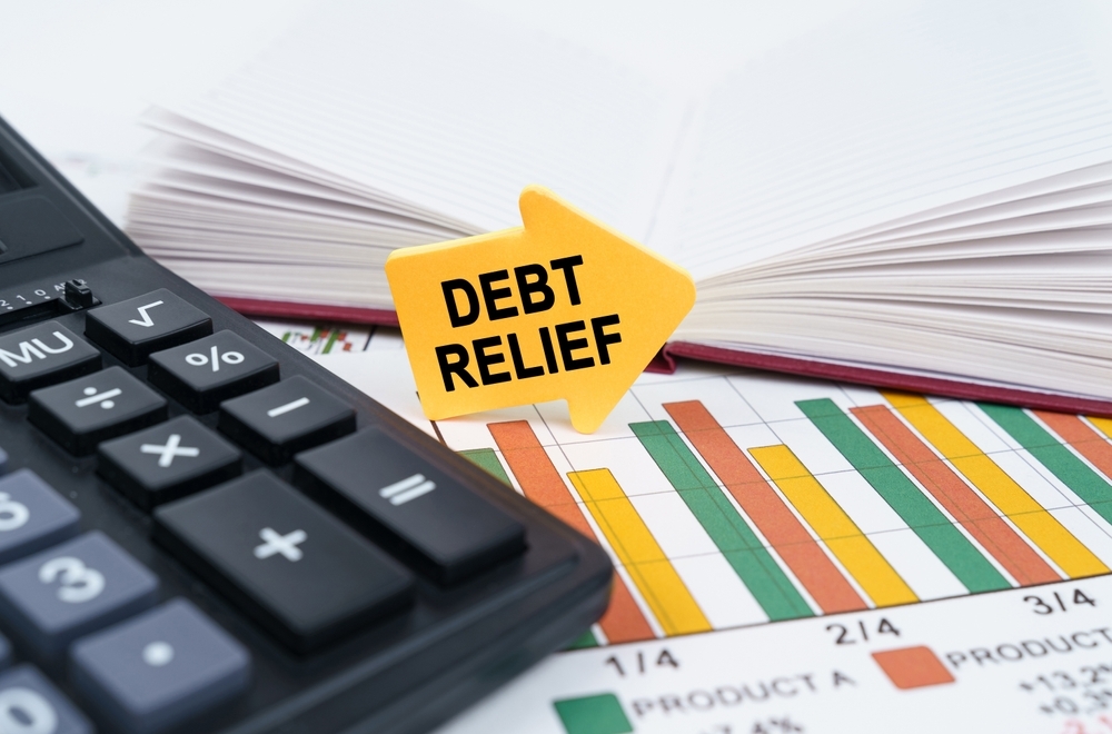 Debt relief sign on a desk with a calculator and financial charts